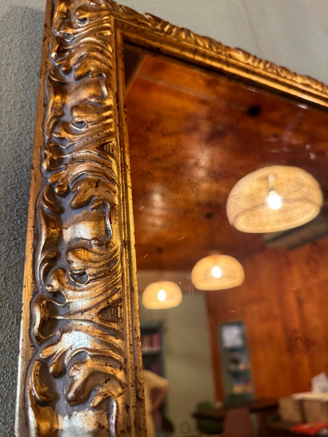 Specchio con cornice dorata che riflette le luci del locale
